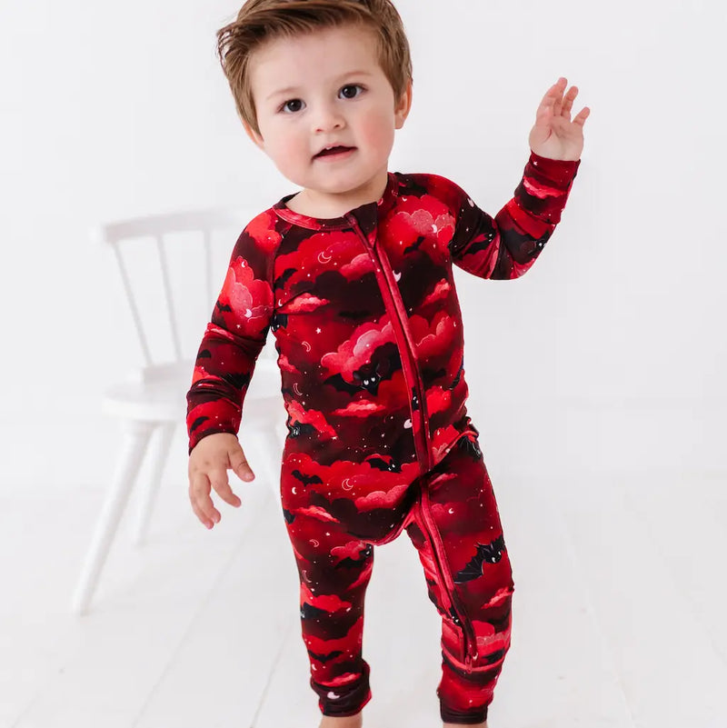 Child wearing a red and black patterned onesie on a white background