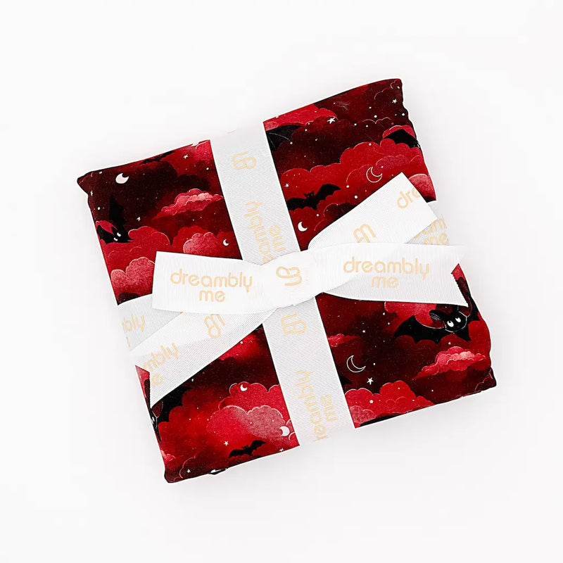 Red and black patterned fabric pouches tied together with a cream 'dreambly me' ribbon, displayed on a white background