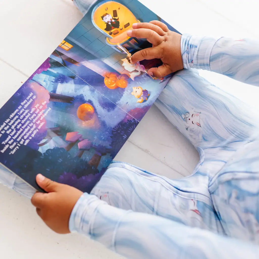 Child wearing a pink and purple patterned shirt with fish and floral designs on a light blue background