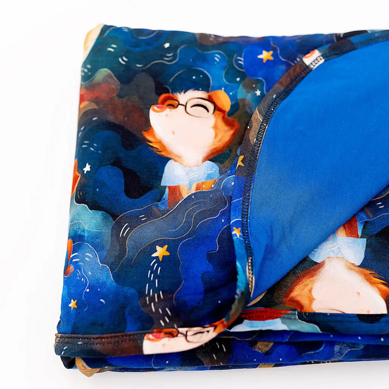 Colorful folded blanket featuring a whimsical cartoon character in a starry night design
