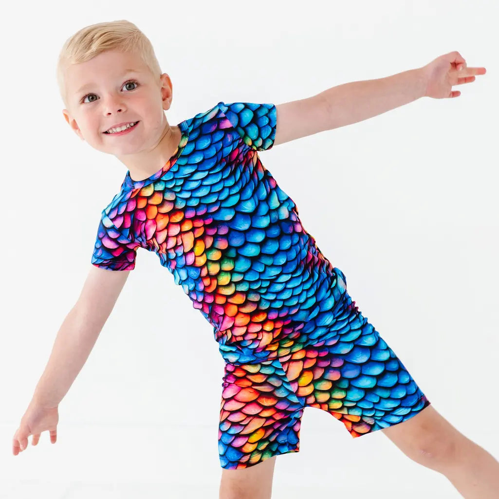 Child wearing a colorful dragon scale patterned outfit on a white background
