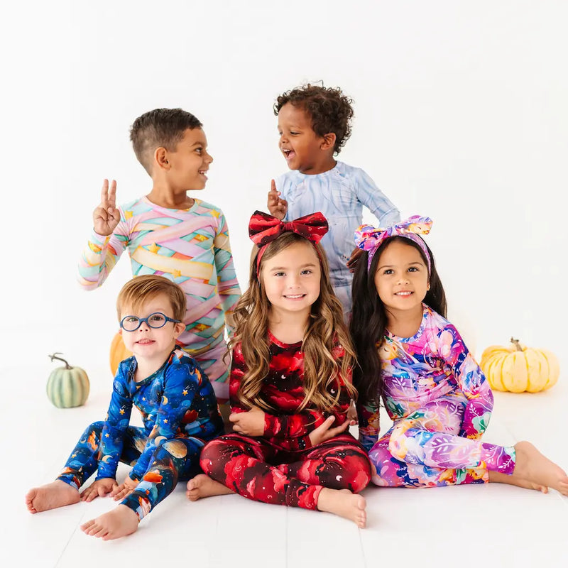 Five children wearing colorful pajamas on a white background with pumpkins.
