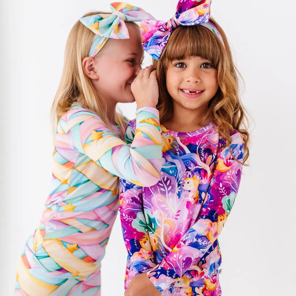 Two children wearing colorful outfits with headbands on a white background
