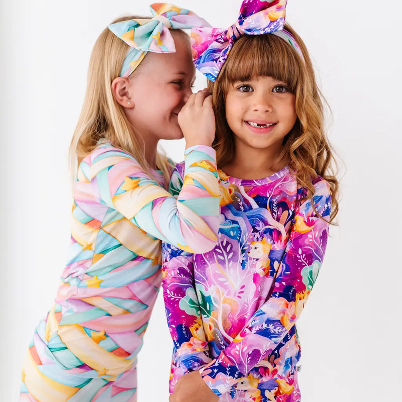 Two children wearing colorful outfits with headbands on a white background