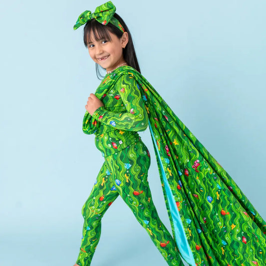 Child wearing a green superhero costume with a cape on a light blue background
