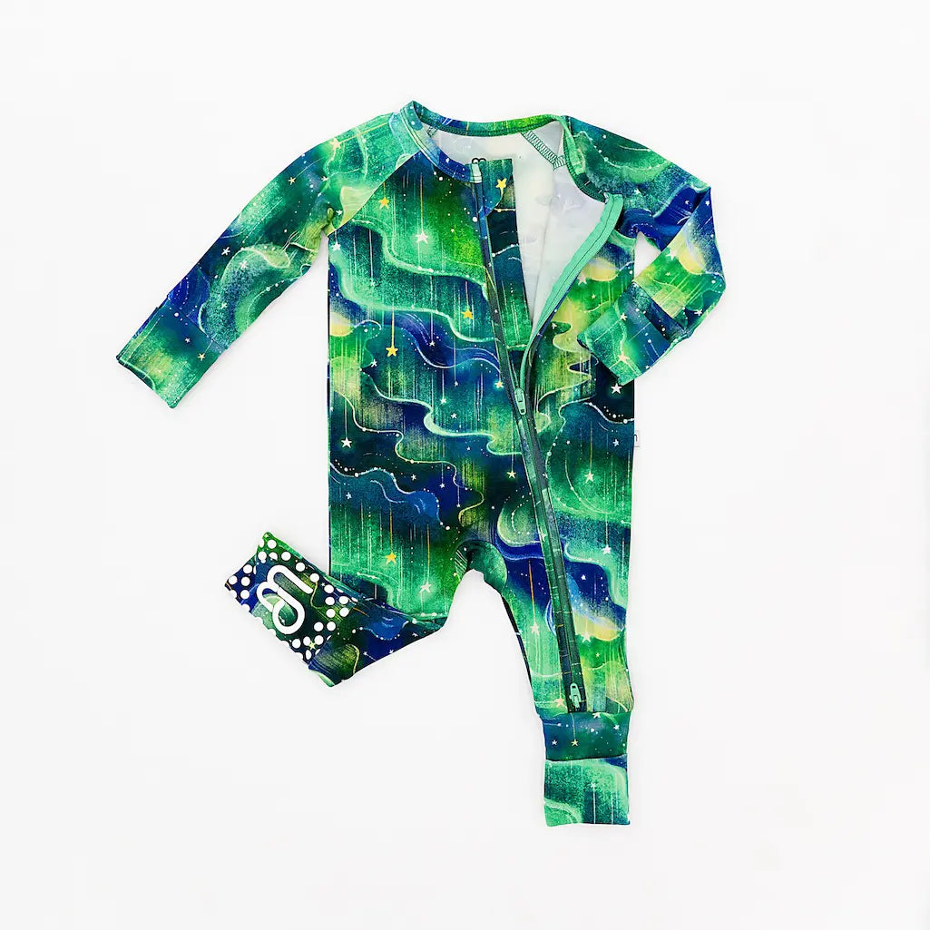 Green and blue patterned baby onesie with a matching headband laid out on a white background