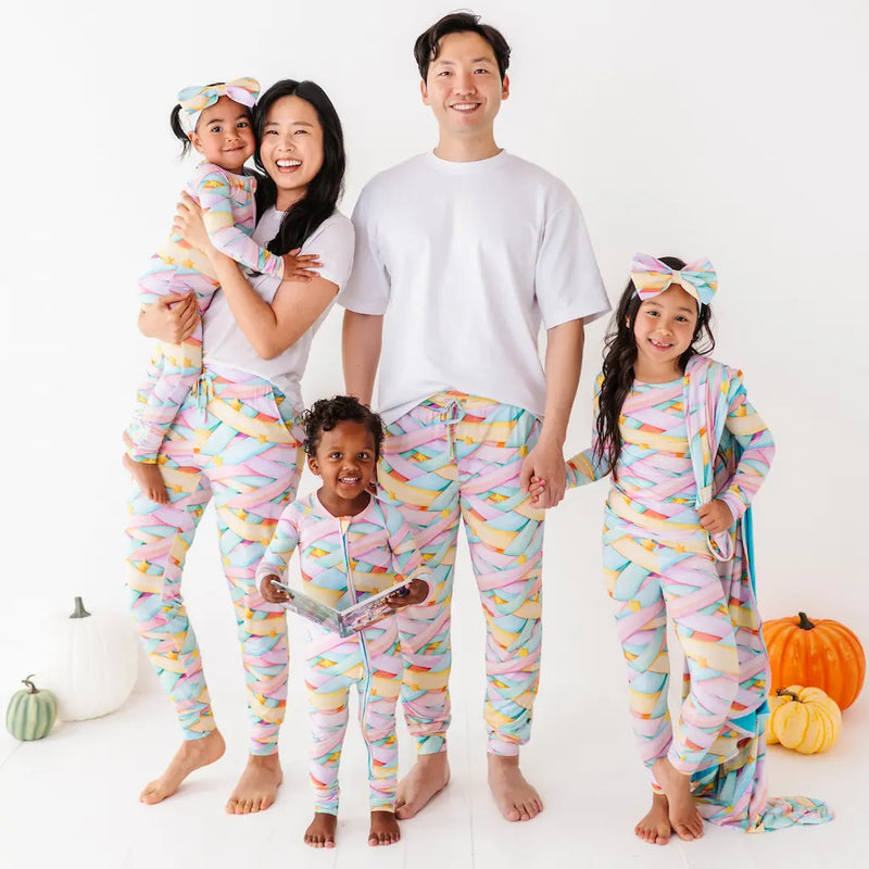 Family of five wearing colorful pajamas with pumpkins in the background