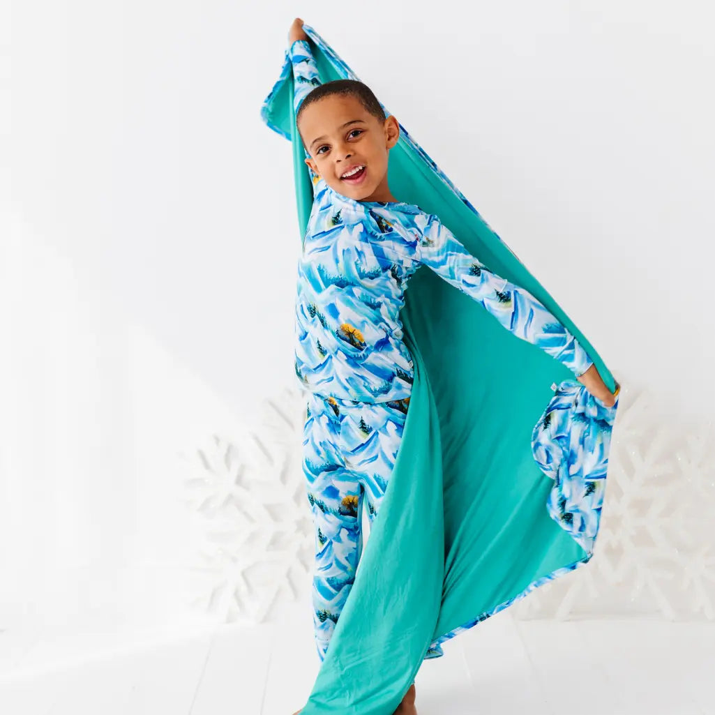 Child wrapped in a blue and green patterned towel on a white background