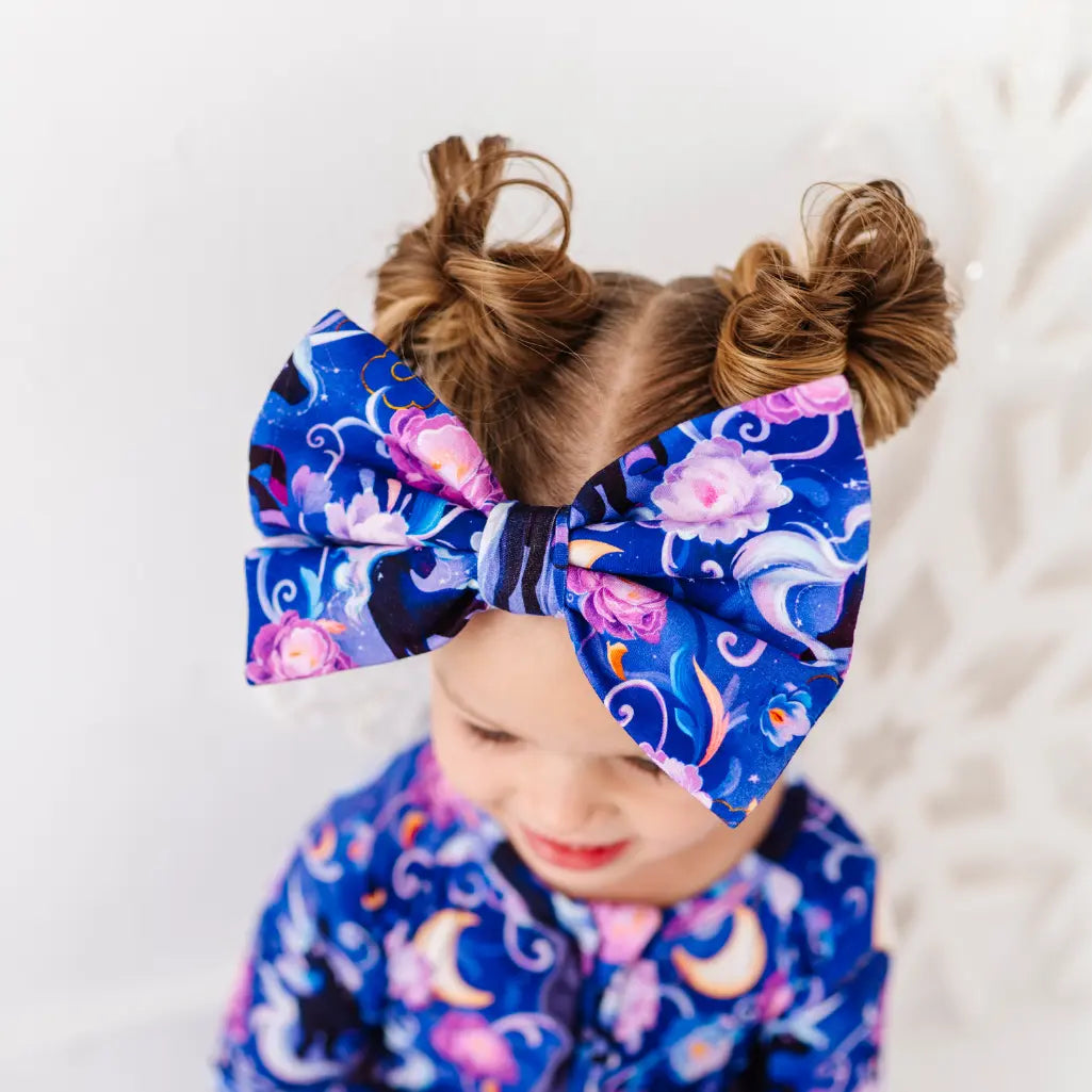 Child wearing a large blue floral bow with pigtails on a white background