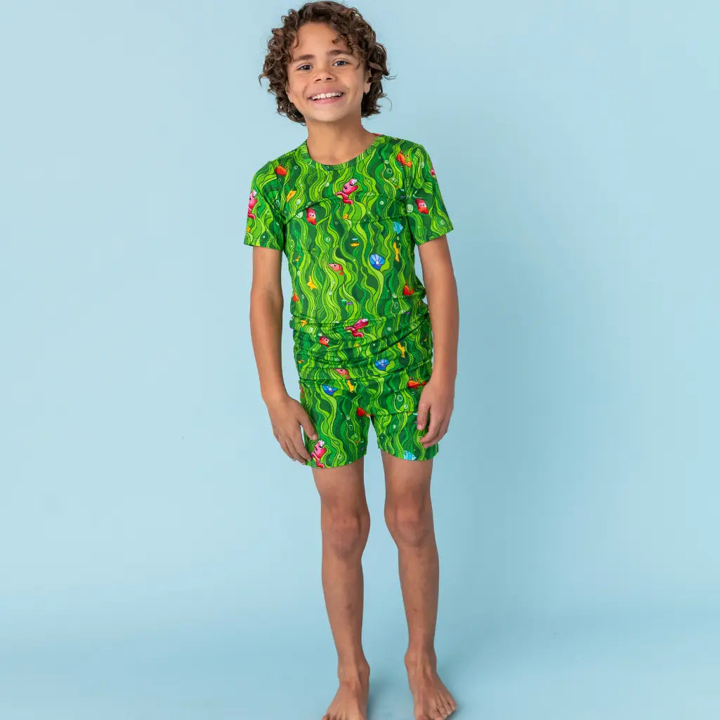 Child wearing a green patterned outfit on a light blue background