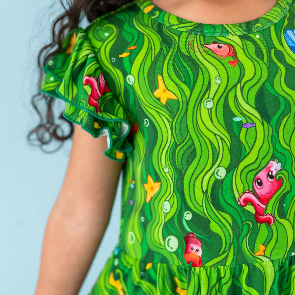 Green dress with underwater-themed design featuring fish and seaweed on a child.