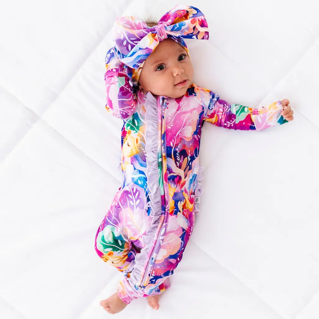Baby in a colorful onesie with a bow on a white background