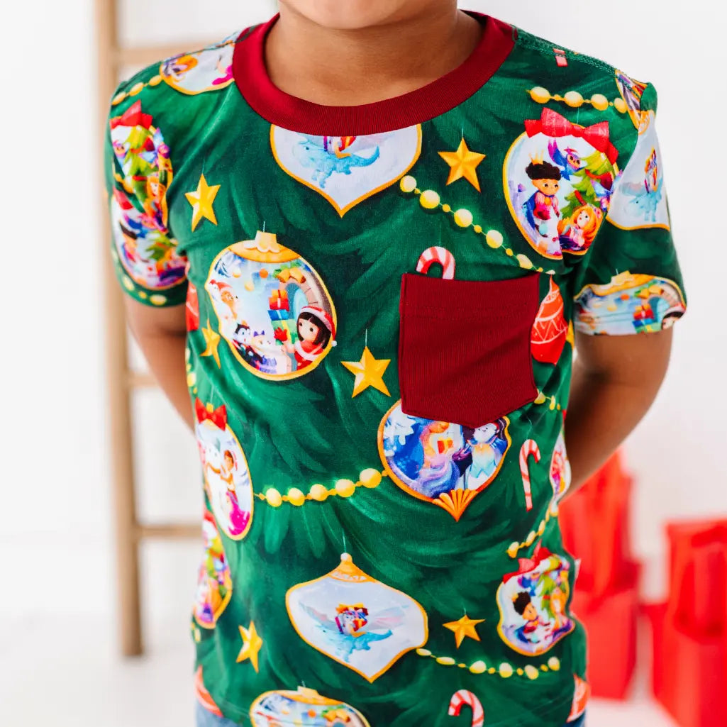 Child wearing a green Christmas-themed pajama with colorful designs on a white background