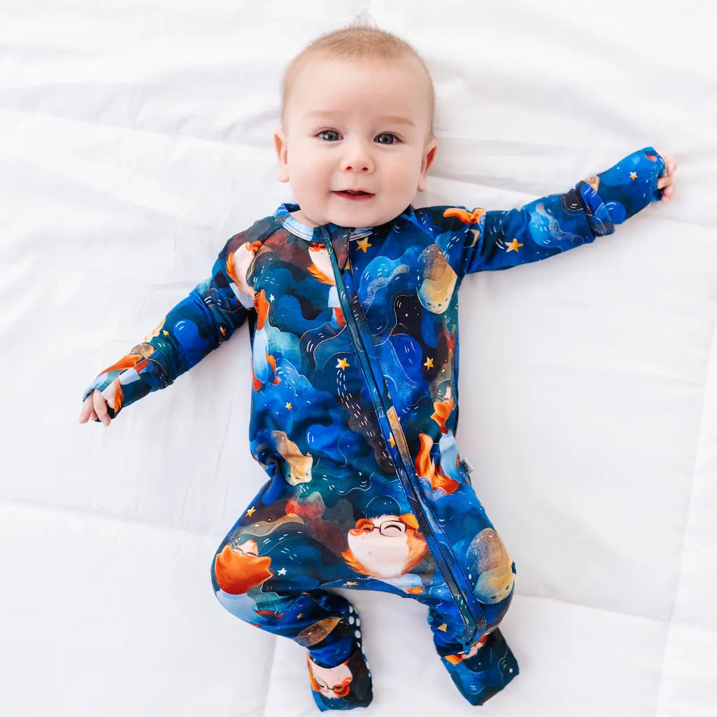 Baby wearing a blue onesie with wolf pattern on a white background