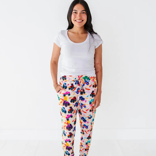 A mother in a white tee wearing women's pajama pants with a colorful monster truck print.