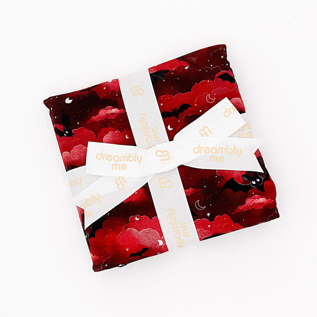 Red and black patterned fabric pouches tied together with a cream 'dreambly me' ribbon, displayed on a white background