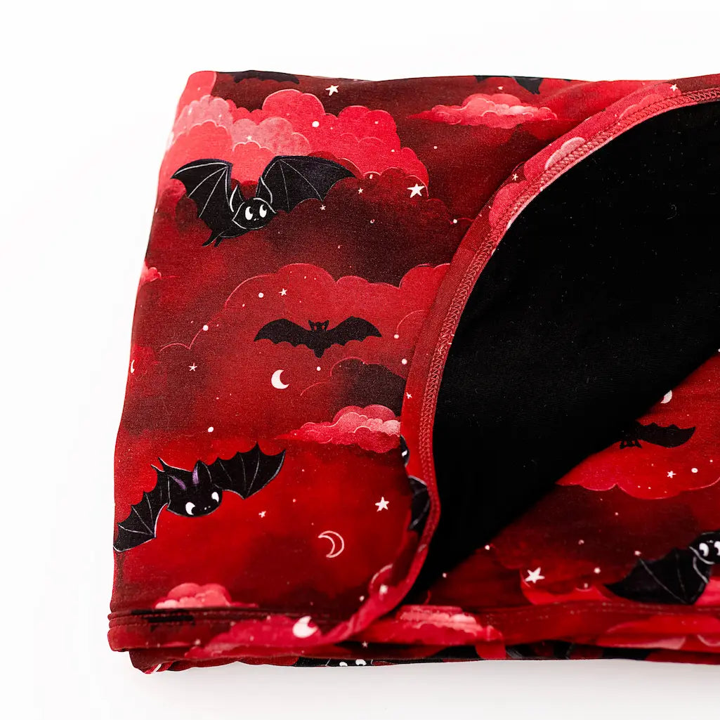 Red blanket with black bat pattern on a white background