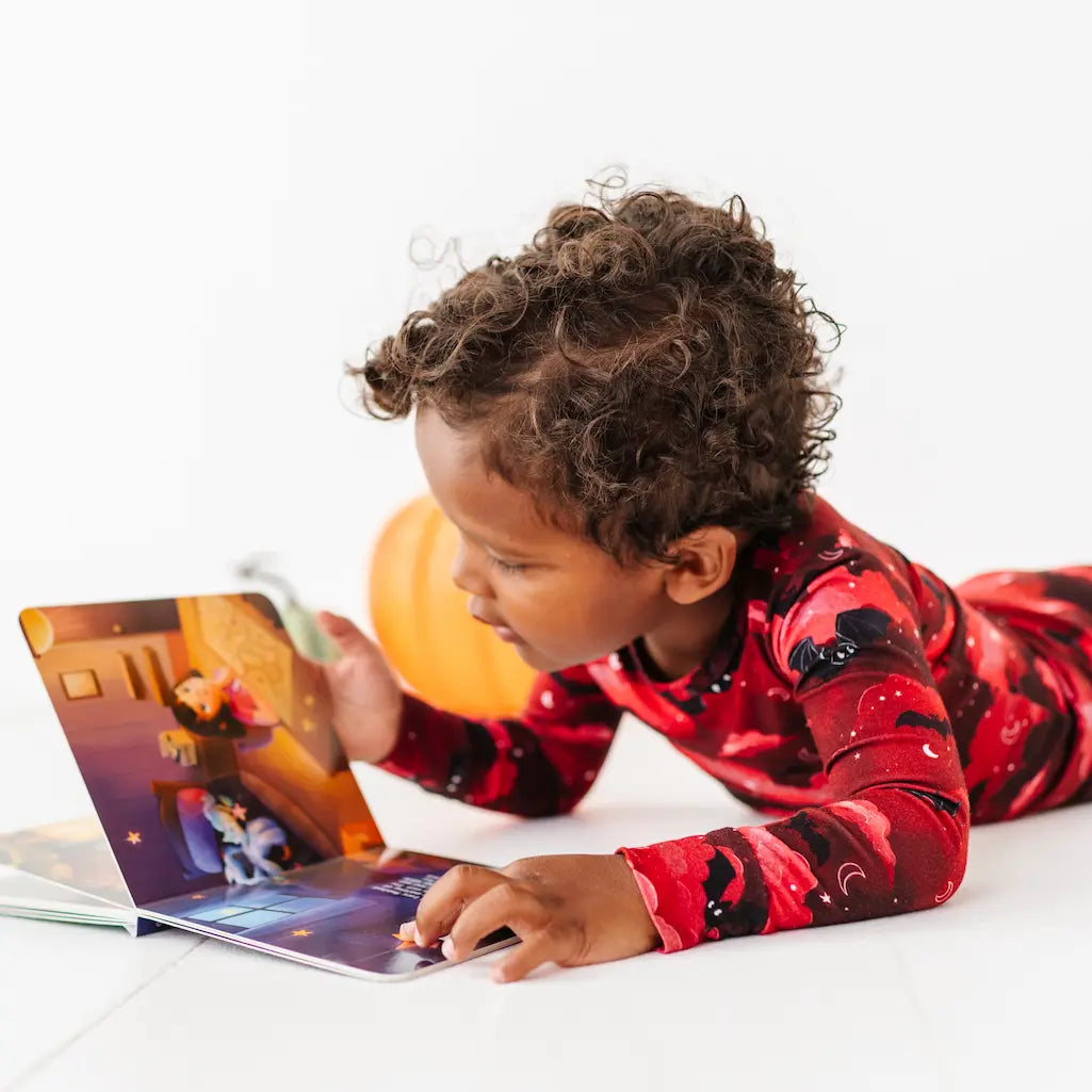 Child in red pajamas interacting with a tablet on a white surface