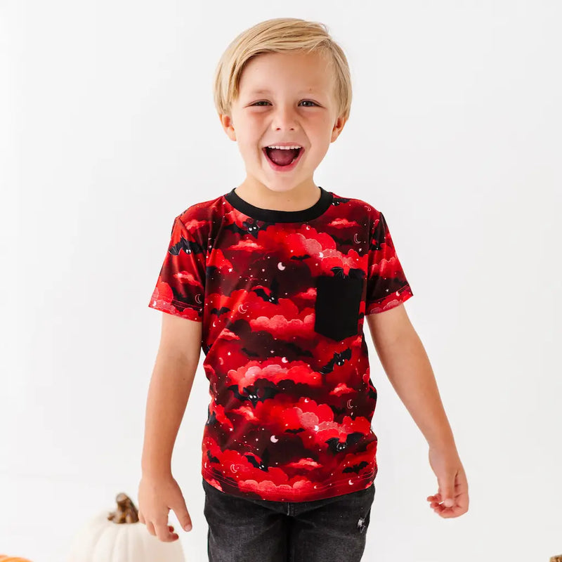 Child wearing a red and black patterned shirt on a white background