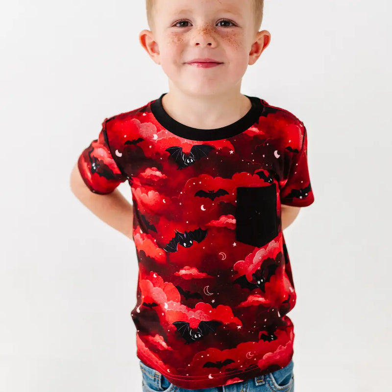 Child wearing a red and black patterned shirt on a plain background
