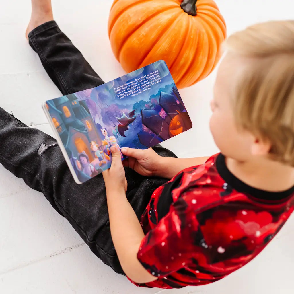 Child holding a colorful book with a pumpkin in the background