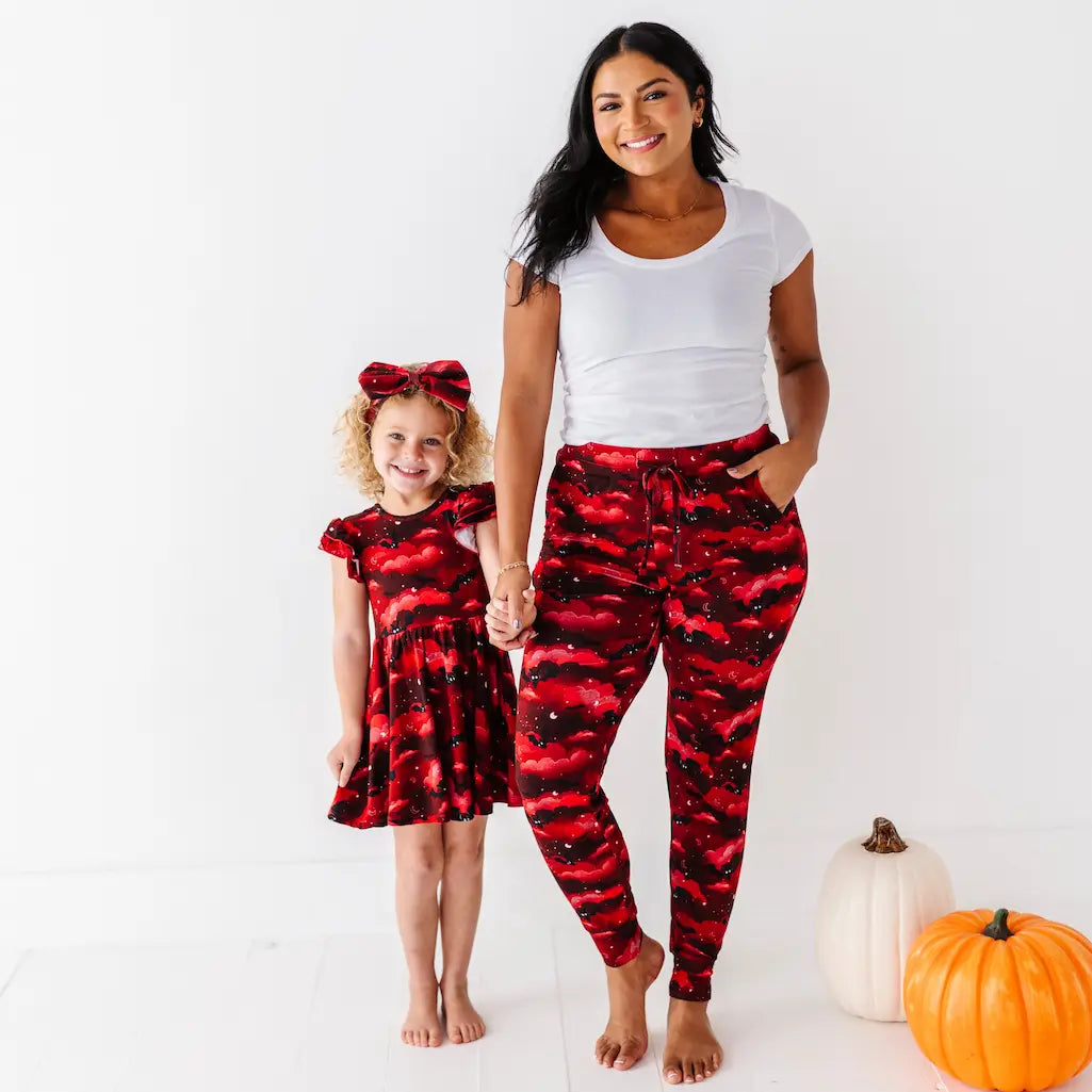 Woman and child wearing matching red and black outfits with pumpkins in the background
