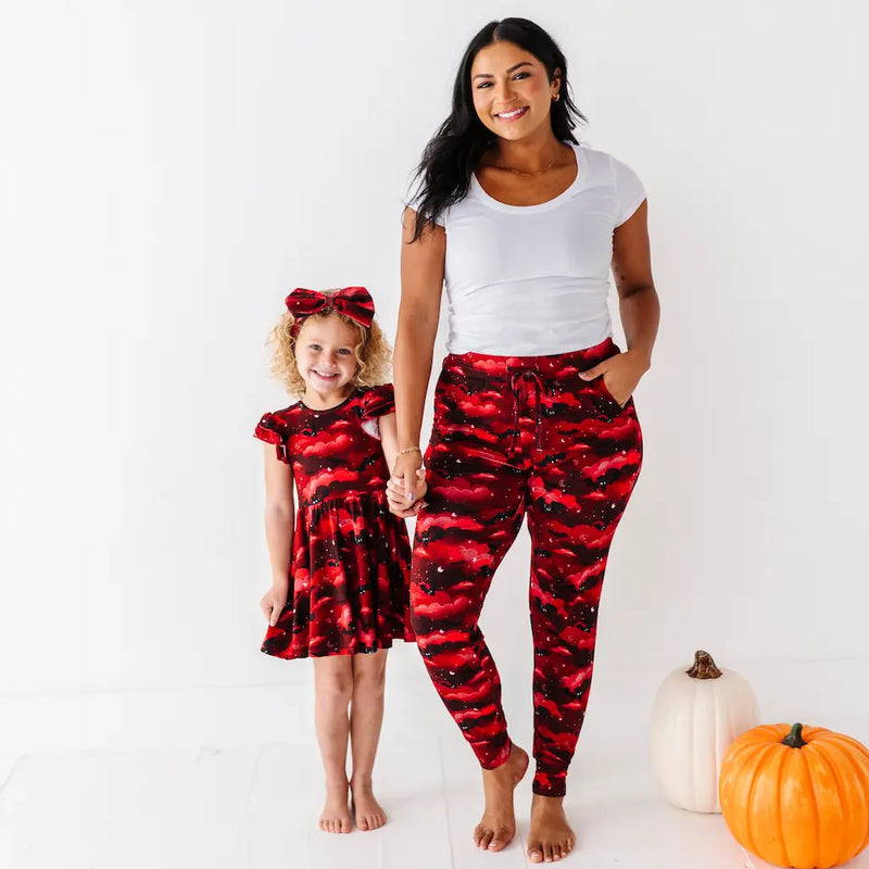 Woman and child wearing matching red and black outfits with pumpkins in the background