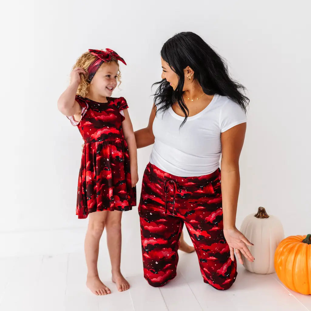 Woman and child wearing matching red and black outfits with pumpkins on a white background