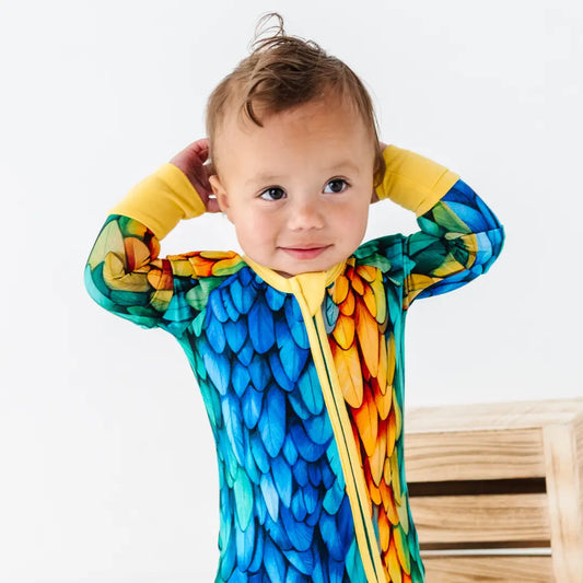 Baby wearing a colorful parrot-themed onesie on a white background