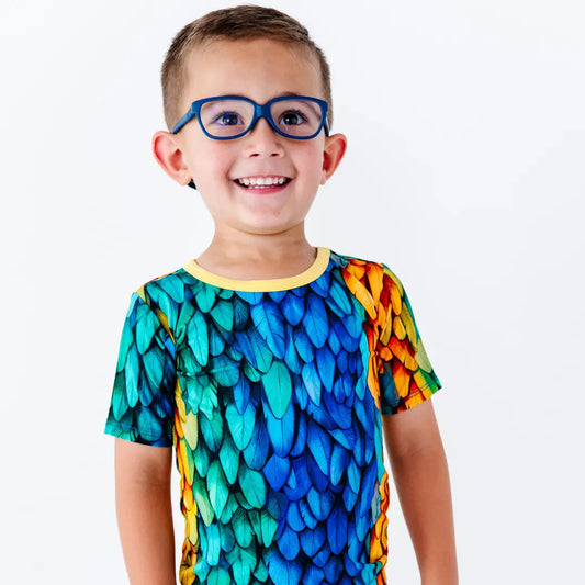 Child wearing a colorful shirt with a dragon scale pattern on a white background