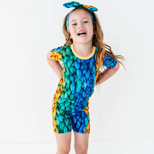 Child wearing a colorful dragon scale-themed outfit on a white background