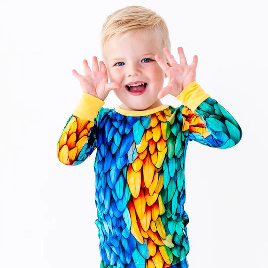 Child wearing a colorful parrot-themed onesie on a white background
