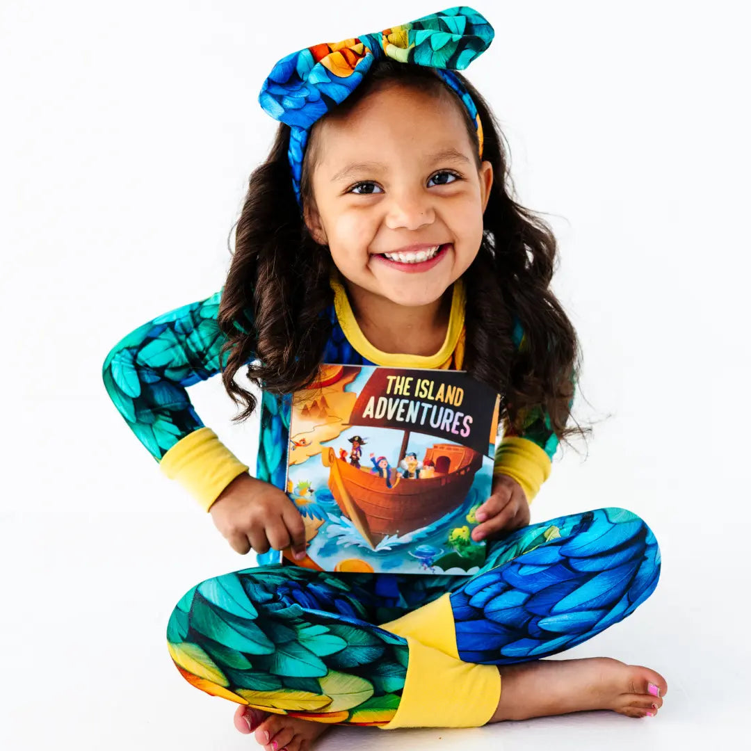 Child wearing a colorful outfit with 'The Island Adventures' design on a white background