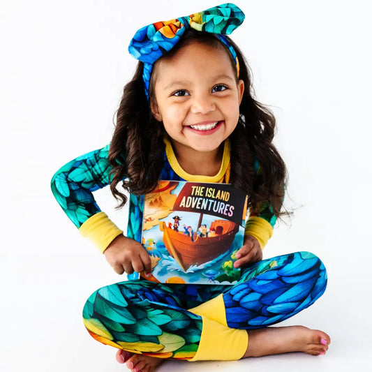 Child wearing a colorful outfit with 'The Island Adventures' design on a white background