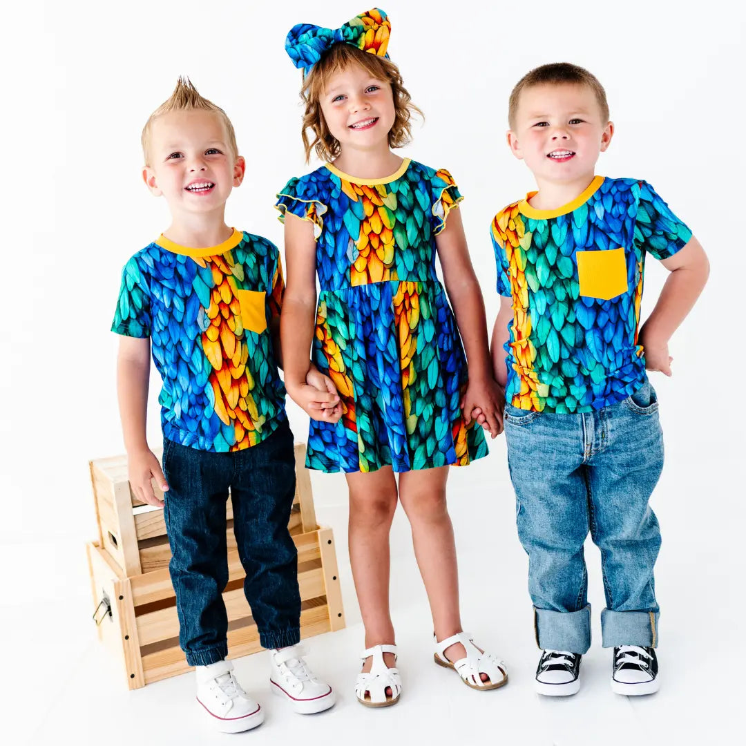 Three children wearing colorful outfits with a white background
