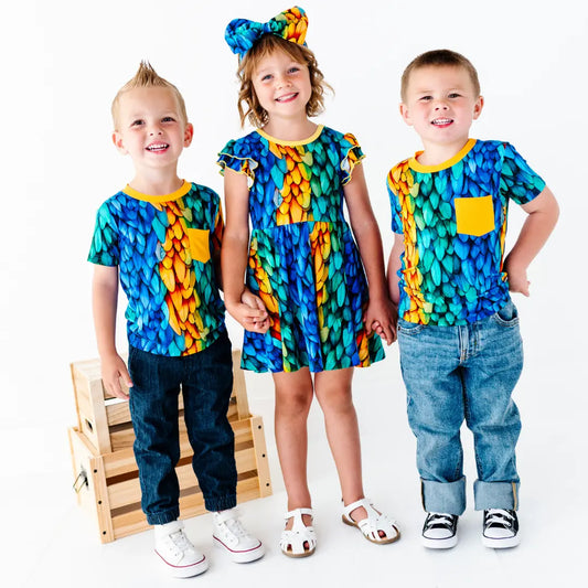 Three children wearing colorful outfits with a white background