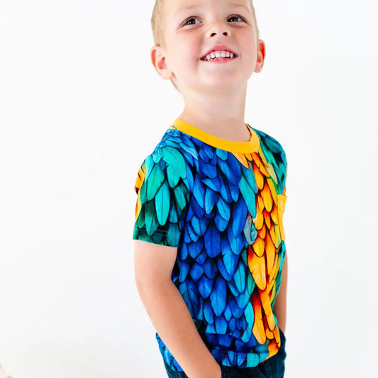 Child wearing a colorful shirt with a leaf pattern on a white background