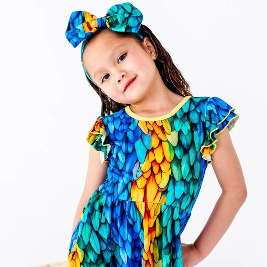 Child wearing a colorful dress with a large bow on a white background