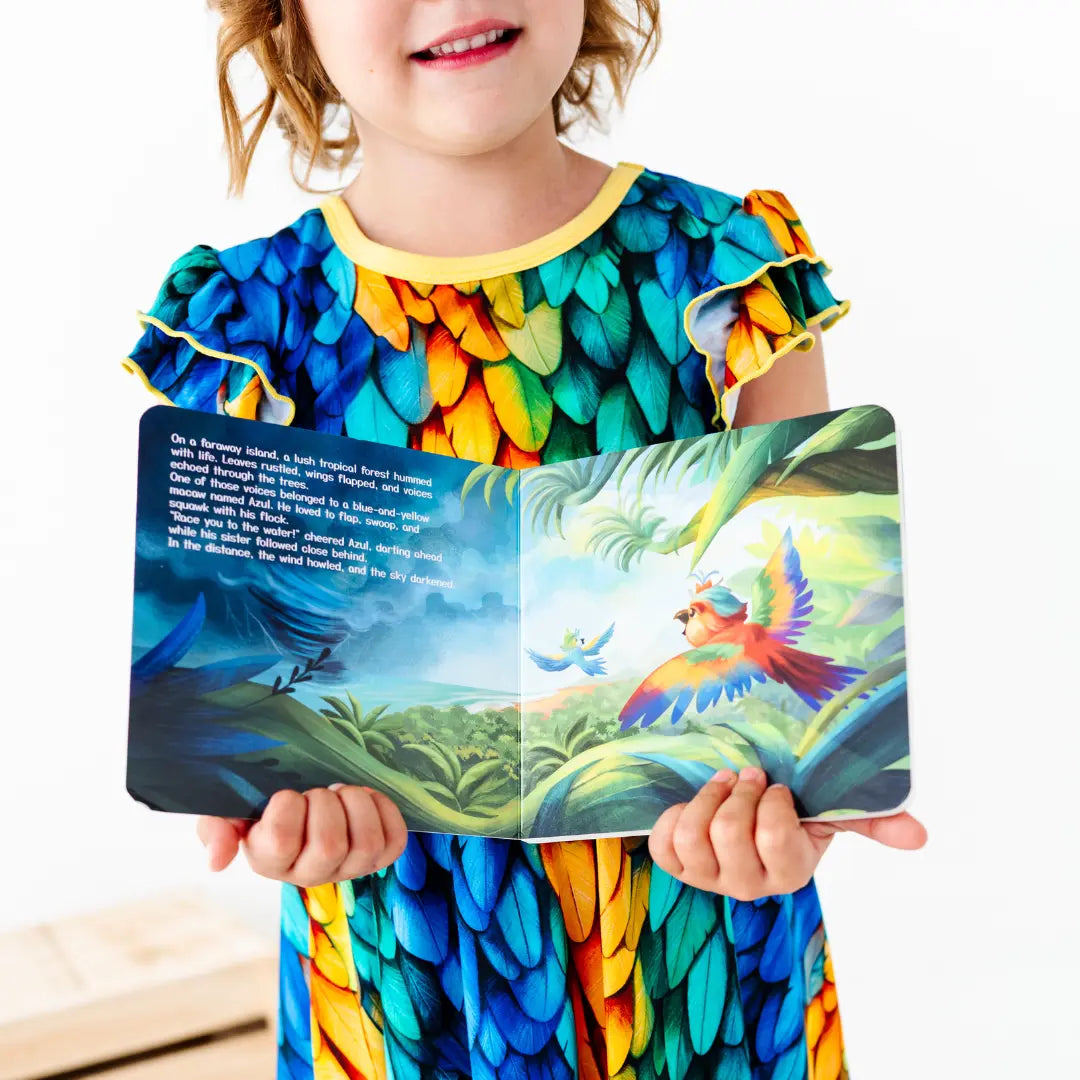 Child wearing a colorful parrot-themed dress holding an open book with a bird illustration.
