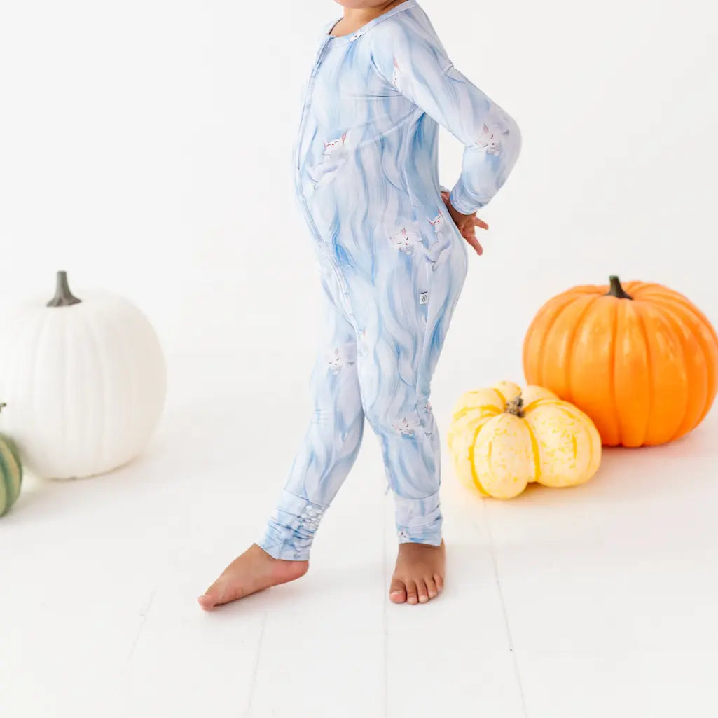 Child wearing a blue tie-dye onesie with pumpkins on a white background