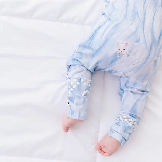Baby wearing a blue and white patterned onesie on a white background
