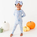 Child wearing a blue tie-dye onesie with pumpkins on a white background