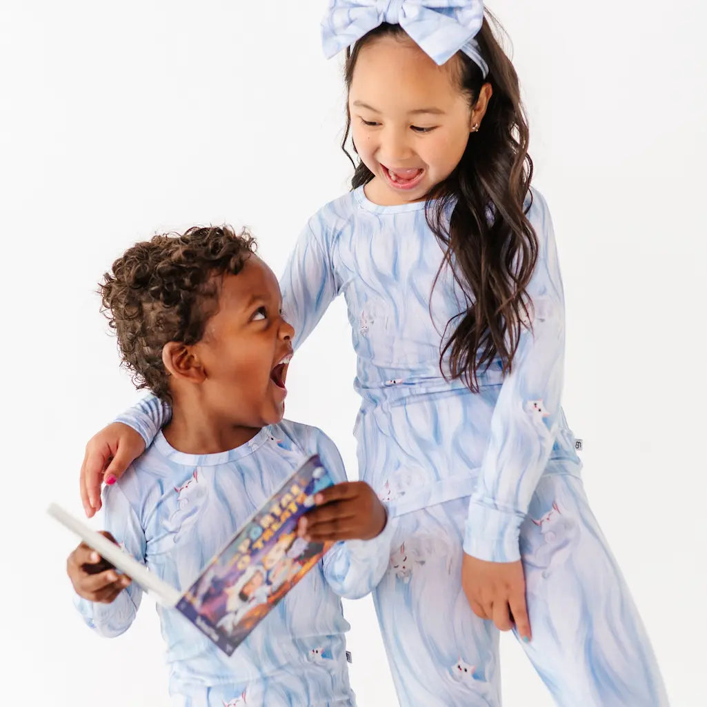 Two children in matching pajama sets with a white background