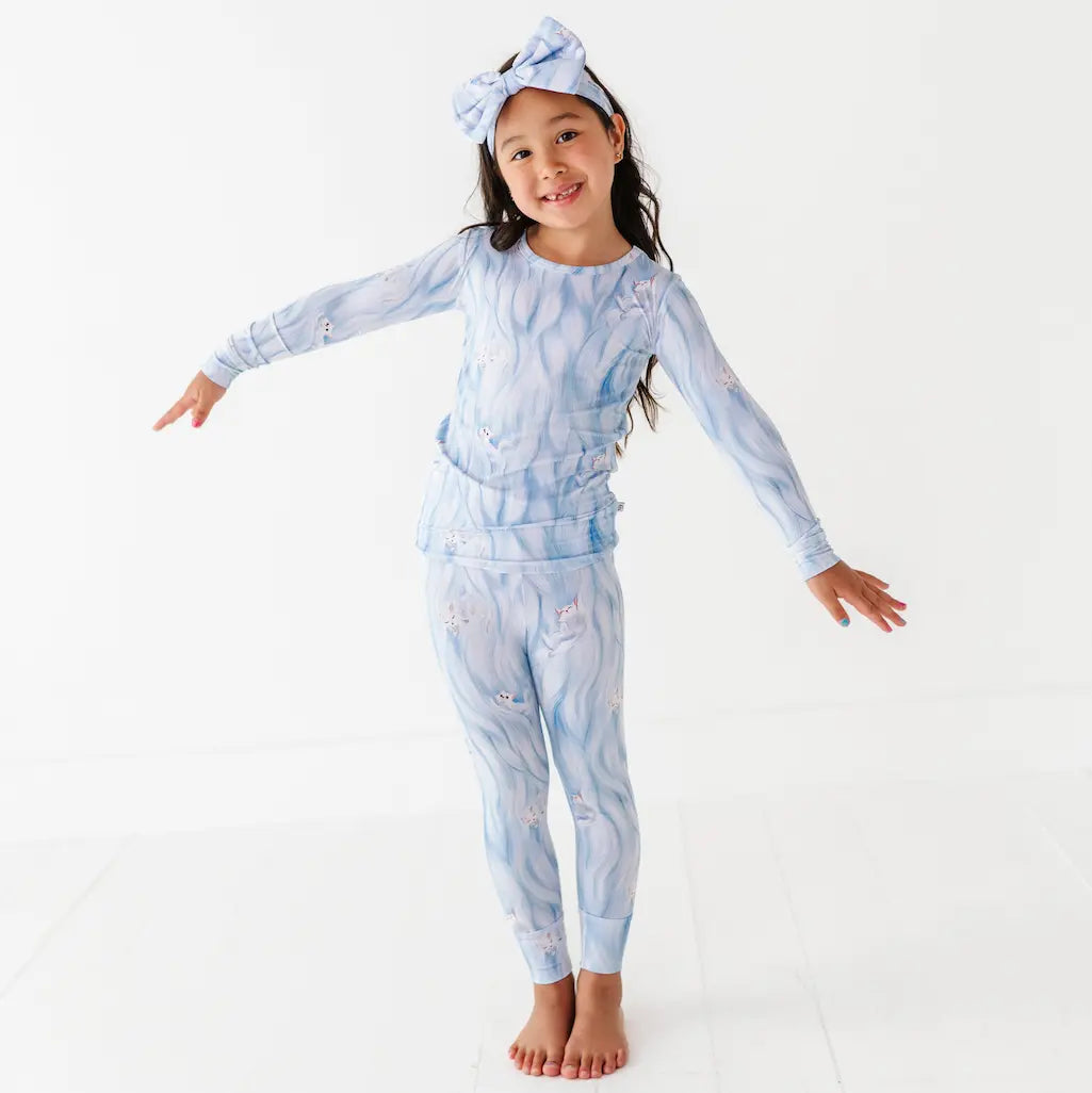 Child wearing a blue tie-dye outfit with a matching headband on a white background