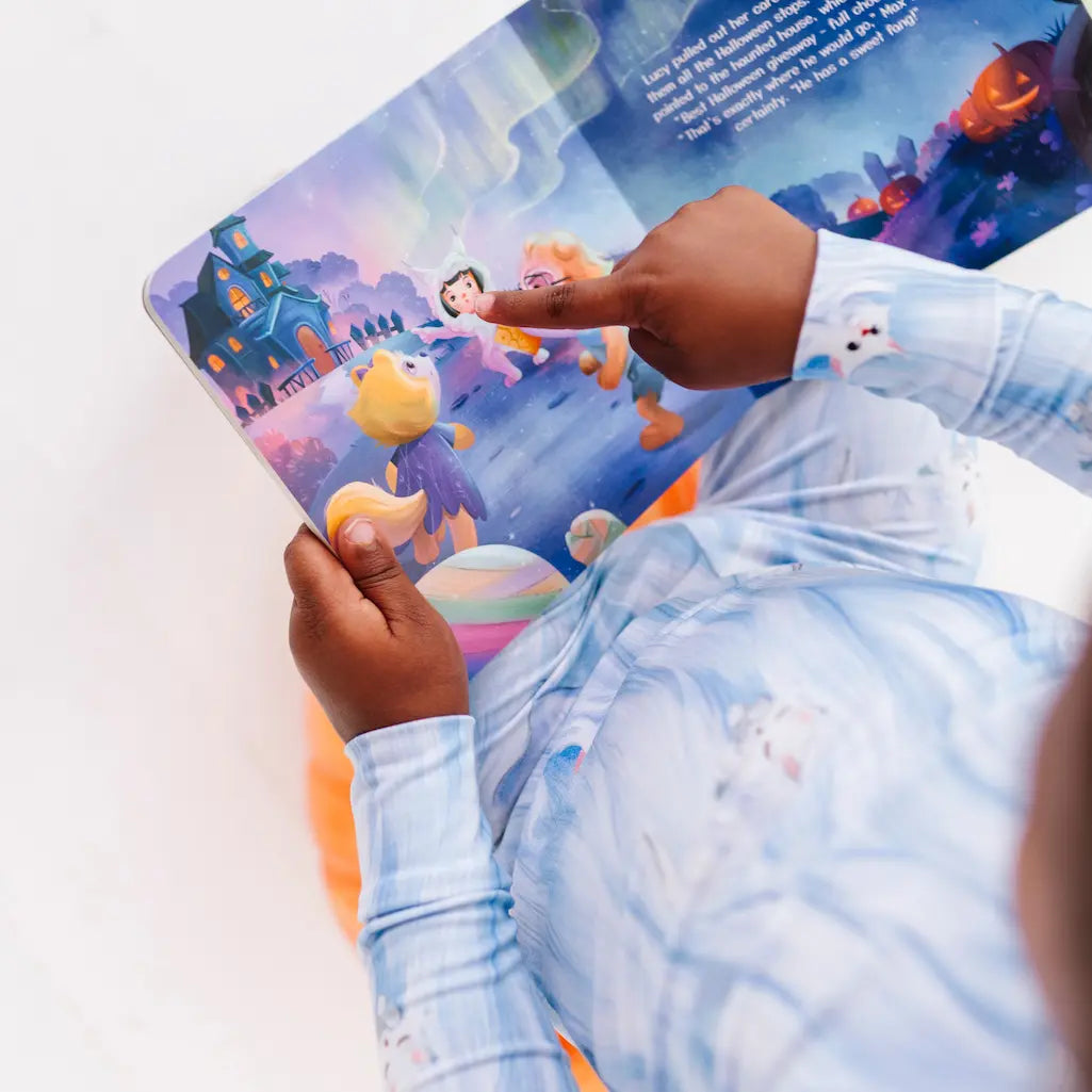 Child reading a colorful children's book with a blue and white striped shirt.