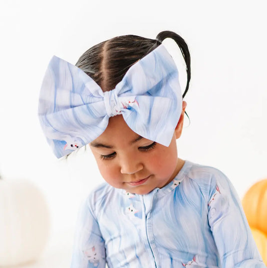 Child wearing a large blue bow headband with a white background