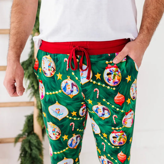 Green Christmas-themed pajama pants with festive designs worn by a person.