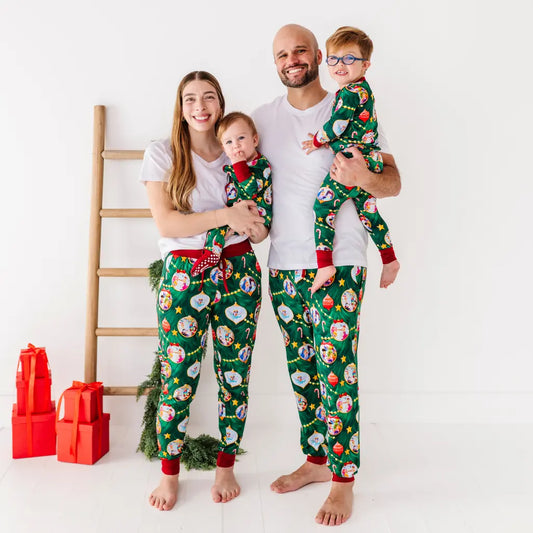 Family of four wearing matching Christmas pajamas on a white background