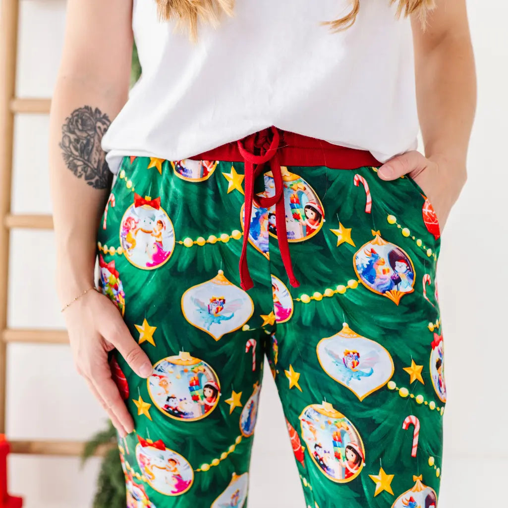 Person wearing festive green pajama pants with cartoon character ornaments on a white background