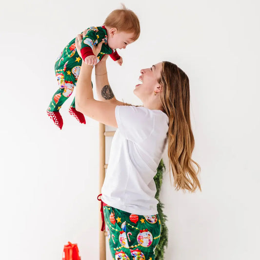Woman and child wearing matching Christmas pajamas against a white background